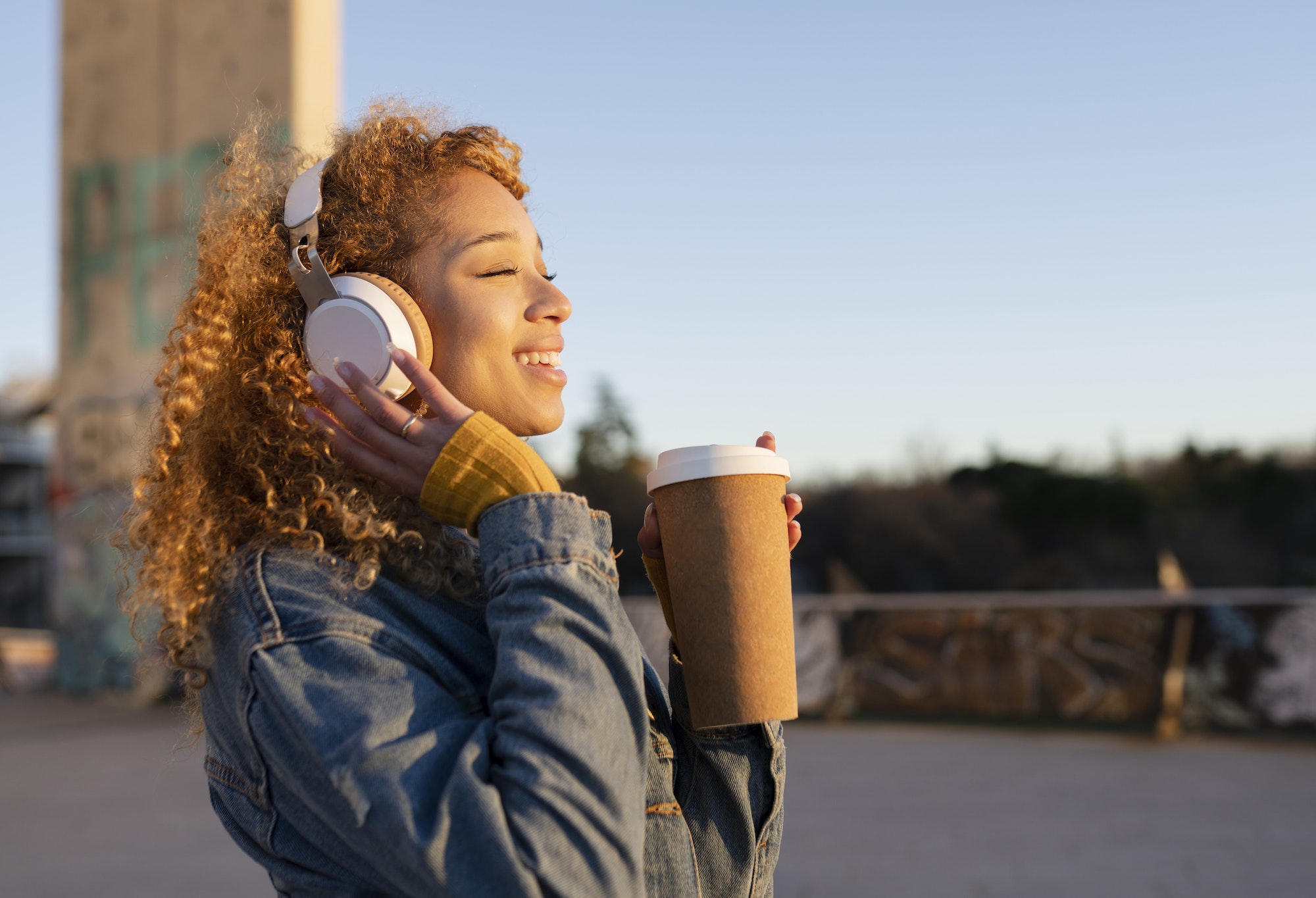 beautiful latin hispanic woman listens to music with headphones and coffee