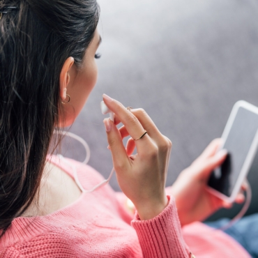 indian woman listening music with earphones and smartphone