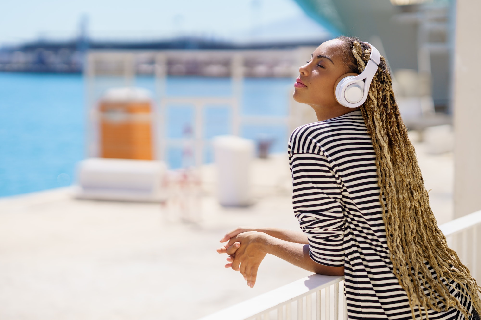 Young black woman listening to music while enjoying the view of the seaport.